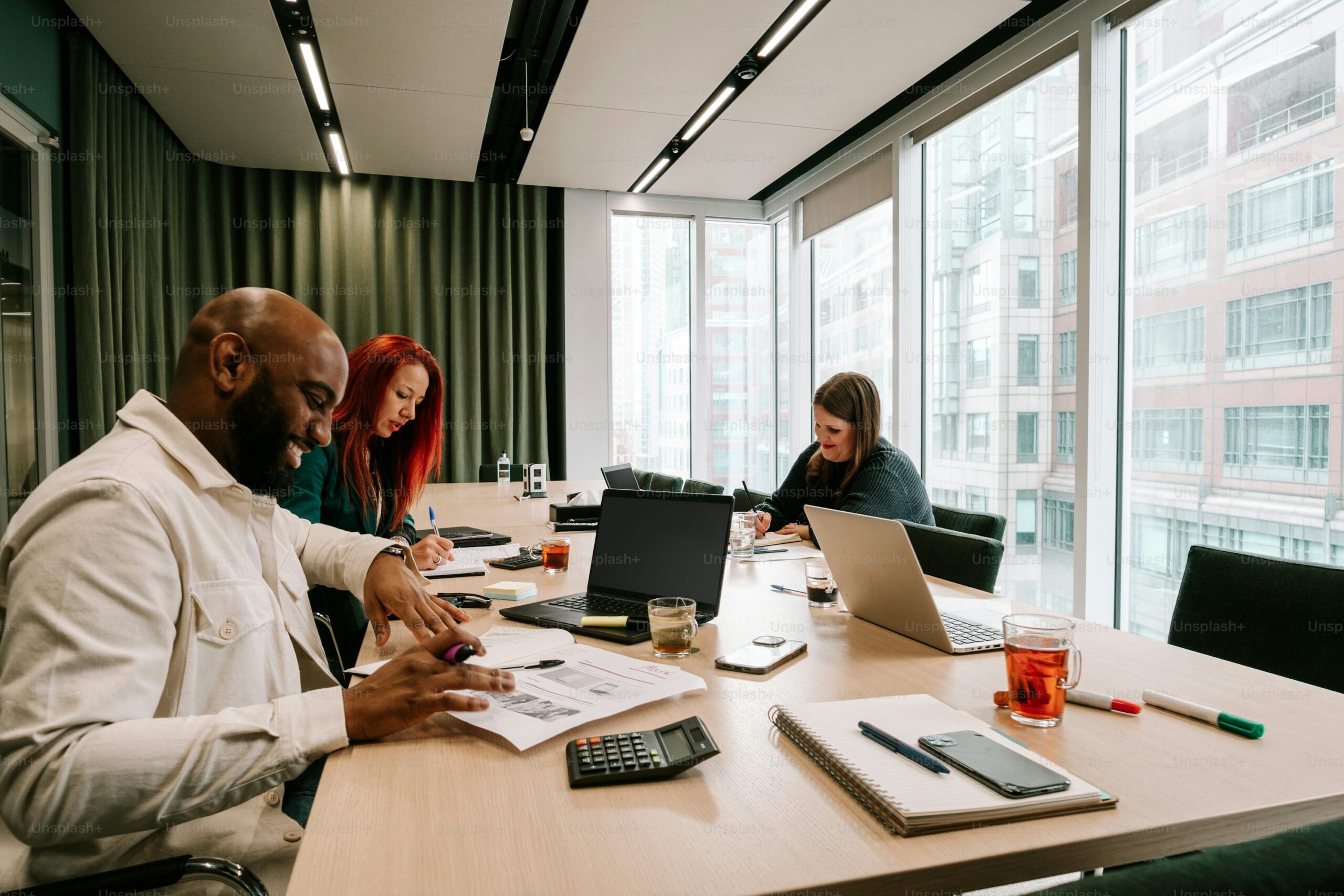 Um grupo de pessoas sentadas ao redor de uma mesa trabalhando em laptops foto – Imagem sobre Agência criativa na Unsplash